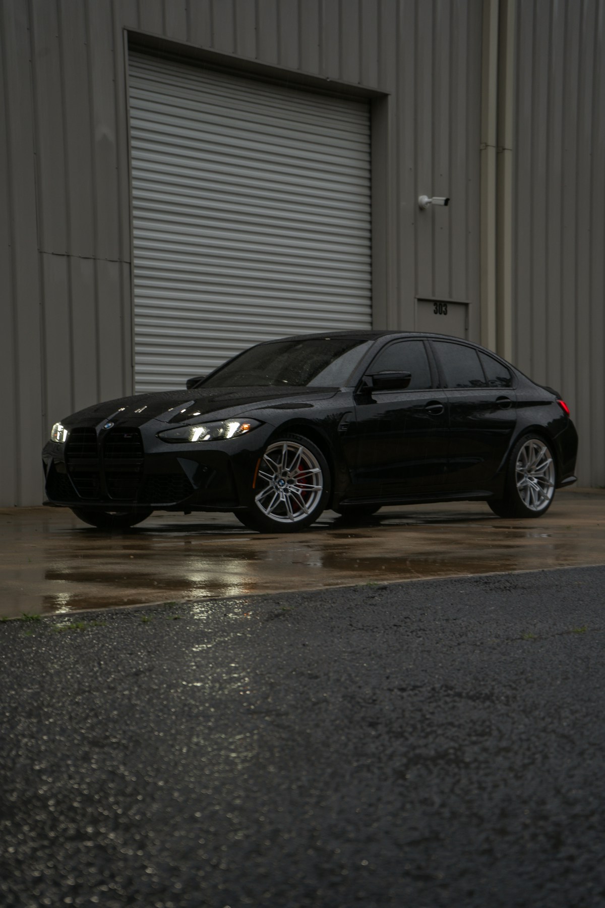 Black sports sedan parked outside a garage